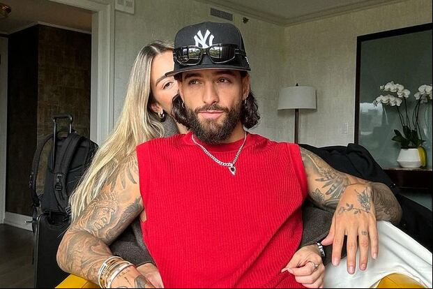 El colombiano posando para la cámara y detrás haciendo un gesto con la mano está su novia Susana Gómez (Foto: Maluma / Instagram)